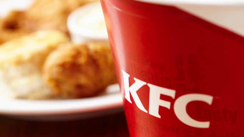 A close-up of a KFC-branded drink, fried chicken, and a biscuit.