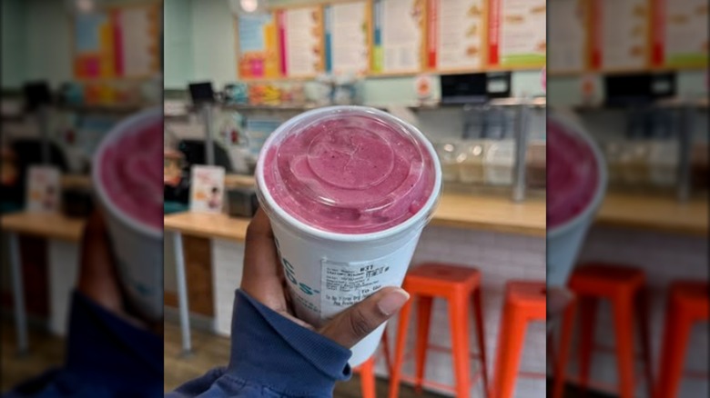 Someone holding a pink smoothie.
