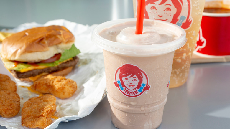 A Wendy's meal consisting of a Frosty, drink, nuggets, and burger arranged on a table