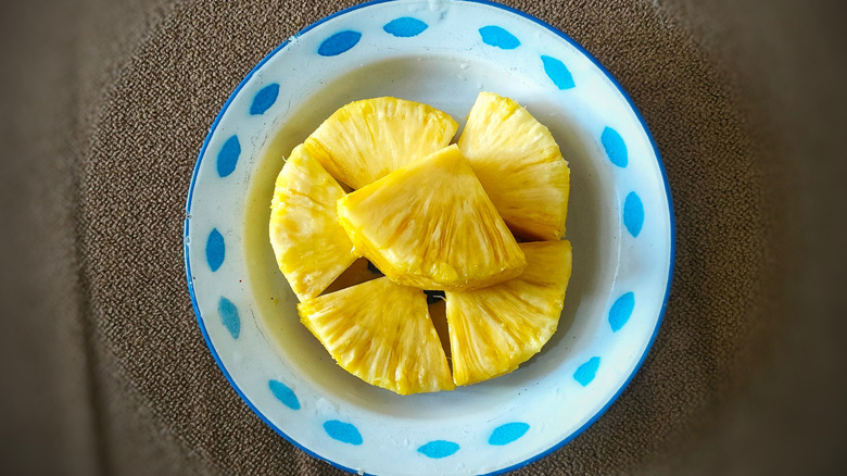 Sliced pineapples on a small plate with blue design elements and lining on the edge.
