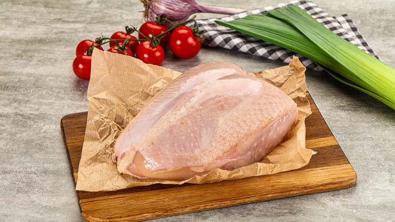 Raw chicken breast on brown paper with vegetables