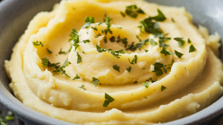 Close-up of a bowl of mashed potatoes with chopped green herbs