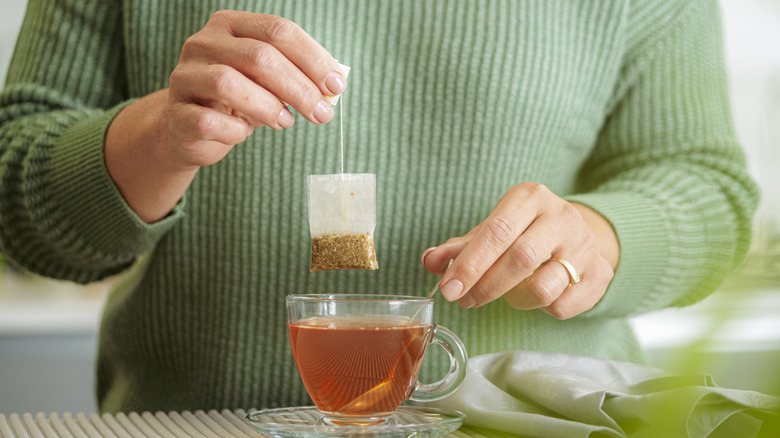 Person dunking a tea bag in a cup of tea