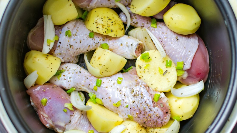 Raw chicken and onions with seasonings in slow cooker