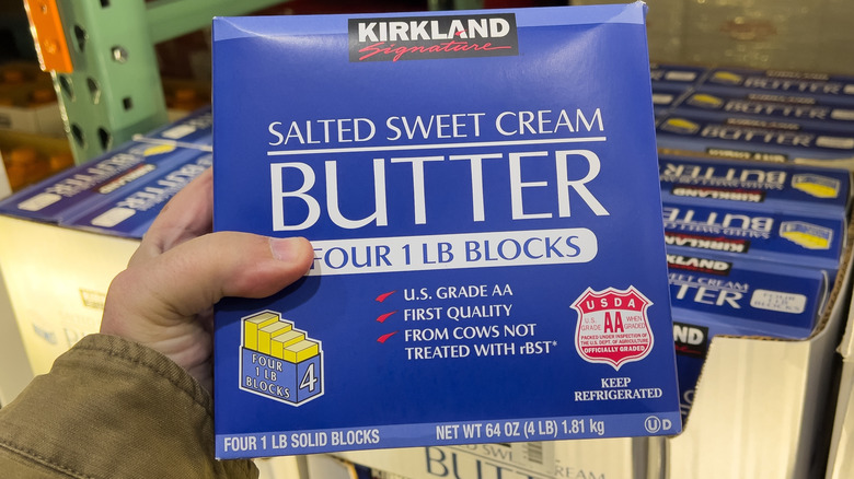 A hand holding box of kirkland signature butter