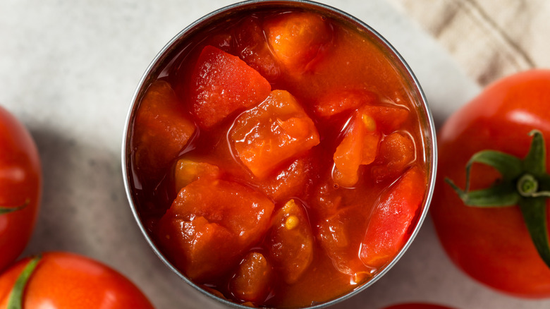 diced tomatoes in open can next to whole tomato