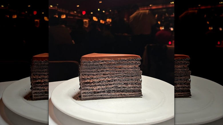 A slice of tall chocolate cake on a white plate