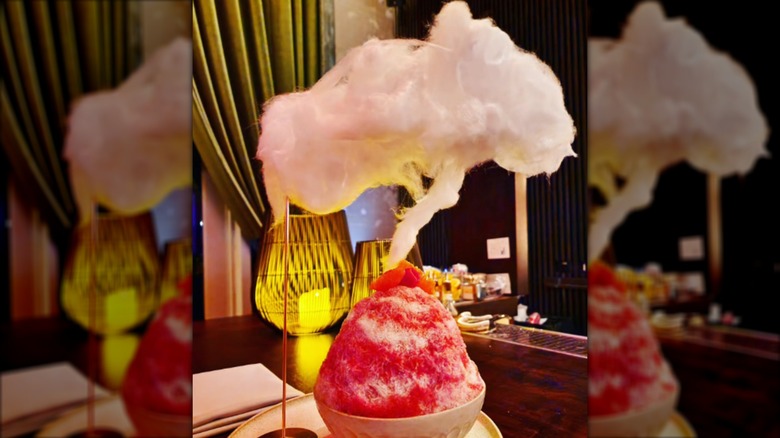 A cotton candy cloud hovering over a bowl of red shaved ice
