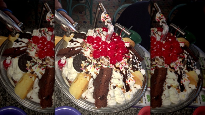 A large sundae filled with ice cream, whipped cream, pastries, and fruit.
