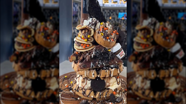 A stack of waffles, pancakes, french toast, candy, ice cream, and toppings.