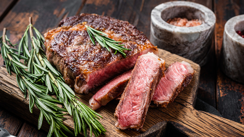 A bone-in grilled ribeye steak with rosemary sprig on top