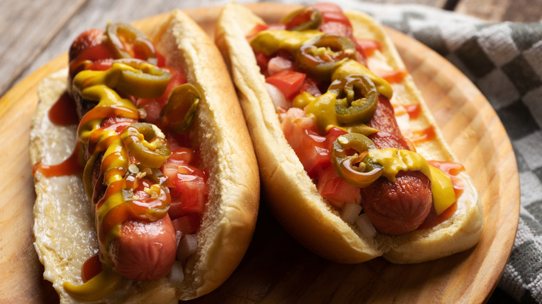 Hot dogs topped with ketchup, mustard, tomatoes, and pickled jalapeños