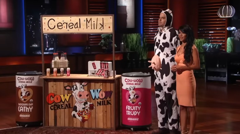 Chris Puoy (in a cow costume) and Tiffany Panhilason next to the Cow Wow Cereal Milk display on Shark Tank