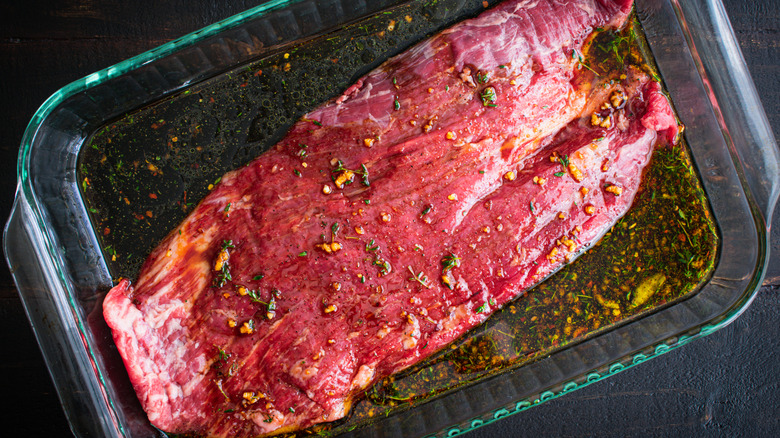 steak marinating in a clear pan
