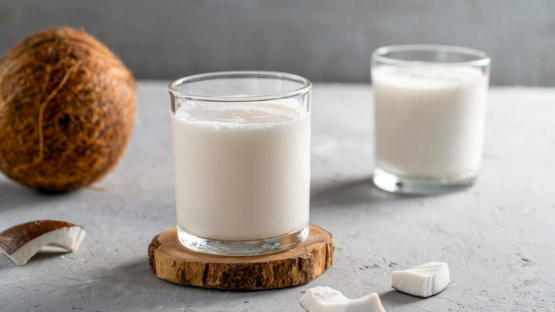 two glasses of coconut milk with coconut in background