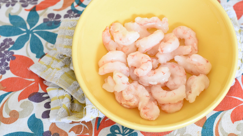 shrimp thawing in a yellow bowl on a table with a colorful floral tablecloth