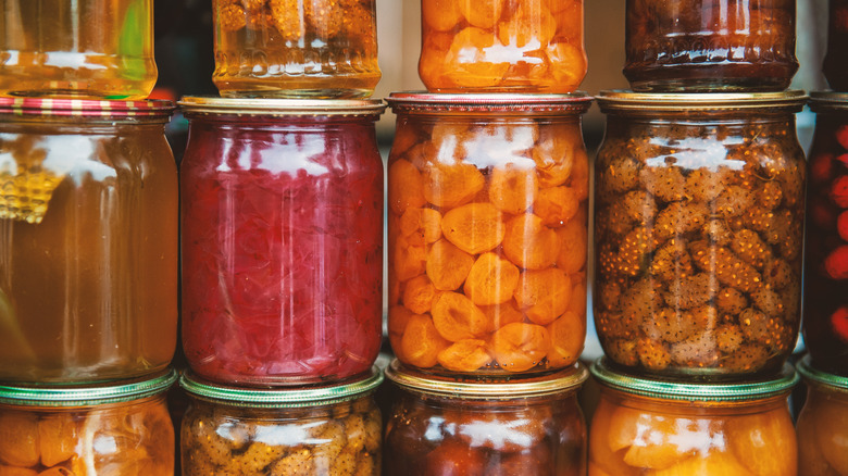 A stack of jars with various canned food items inside.