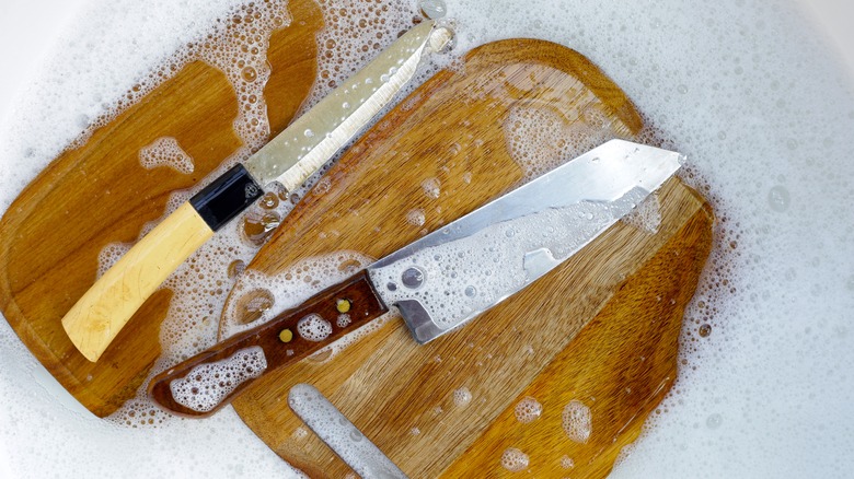 Two cutting boards with knives in water