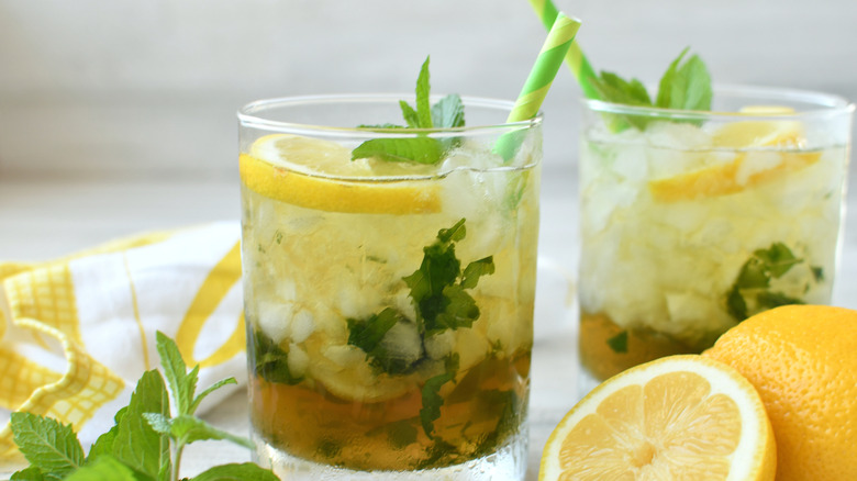 Two glasses filled with a drink of lemon and fresh mint