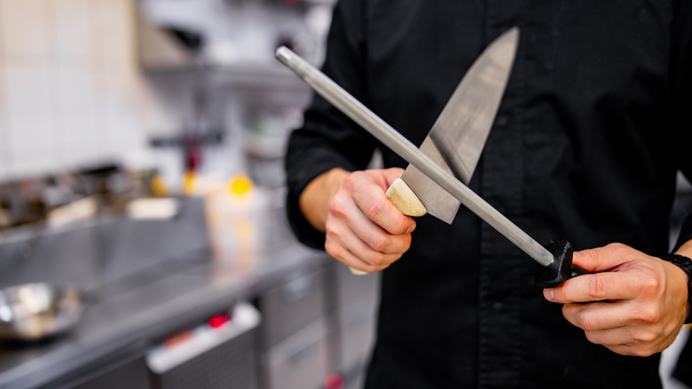 person in black outfit honing a knife