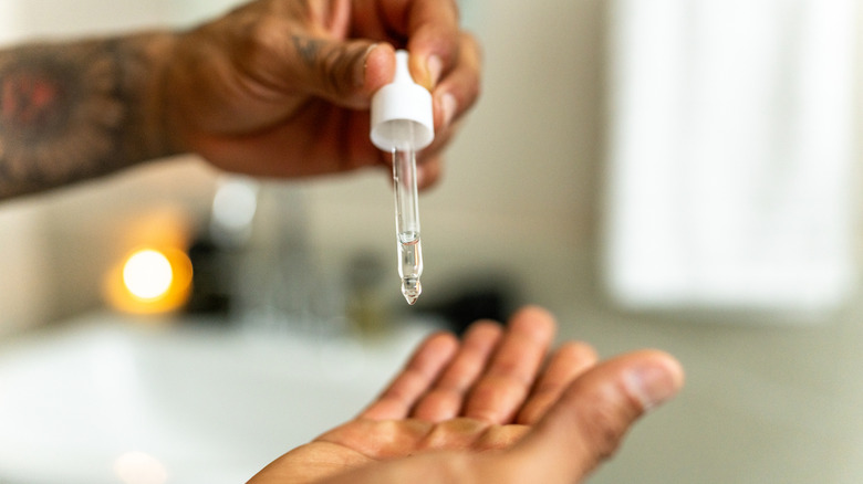 person using small dropper to squeeze oil onto fingers