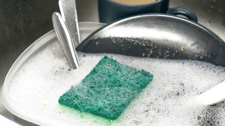 utensils and dishes in soapy water with sponge