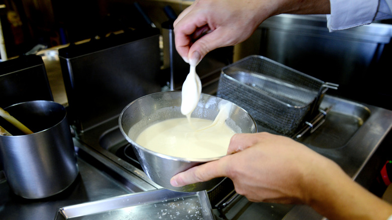 Preparing tempura fish with a hot oil deep fryer in the background