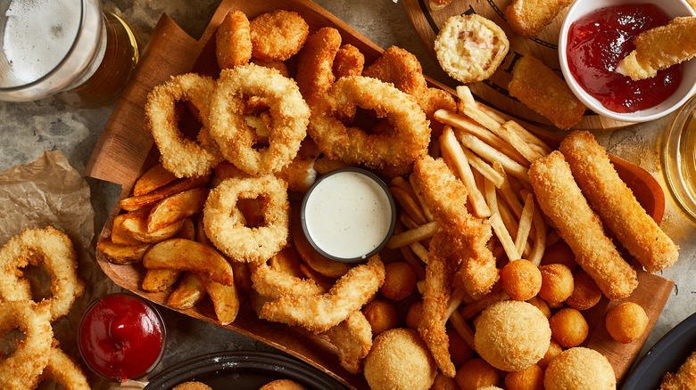High angle view of variety of snacks and a glass of beer on the side
