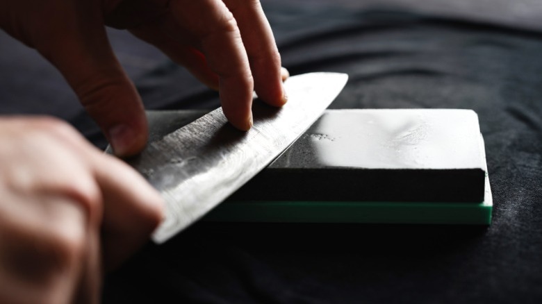 A knife being sharpened on a whetstone.