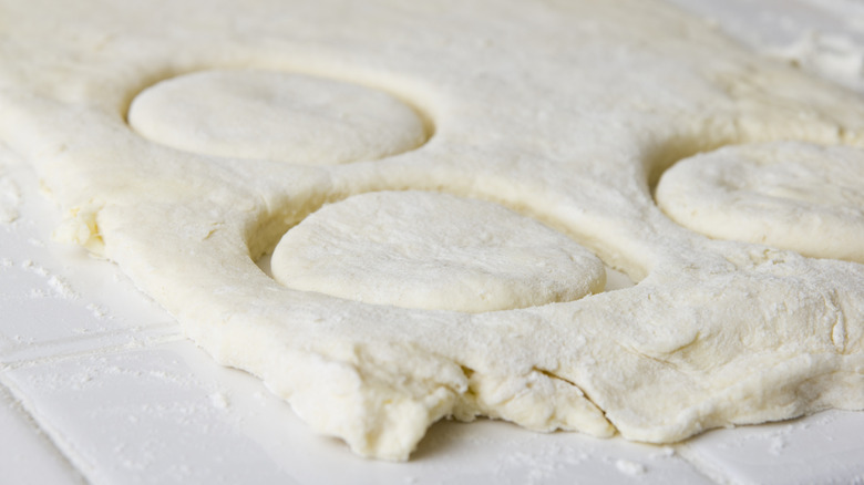 A slab of biscuit dough marked with ring-shaped indentations.