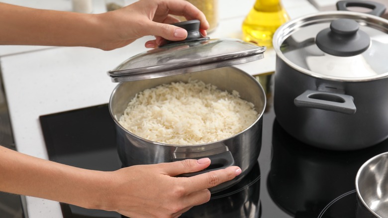 A woman cooking rice on her stove.