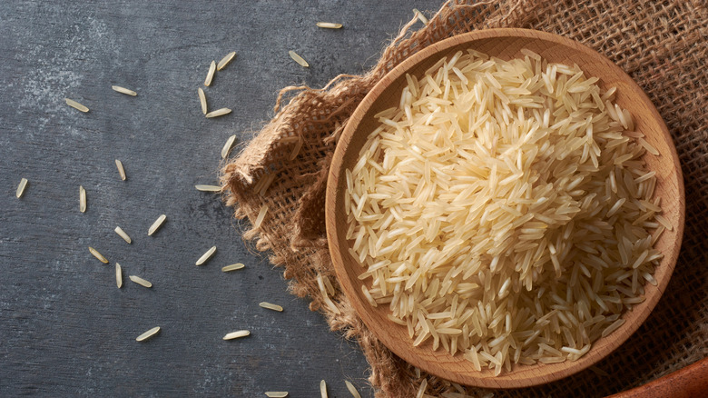 A wooden bowl of raw basmati rice