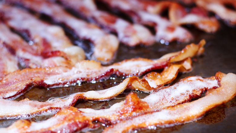Bacon sizzles on a metal cooktop