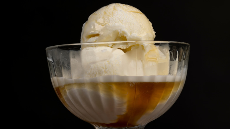 A glass bowl with vanilla ice cream and maple syrup