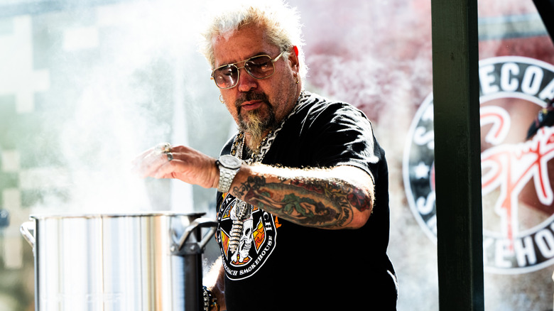 Guy Fieri wearing sunglasses outdoors during a cooking event.