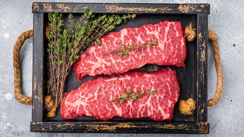 Denver steaks on wood board with herbs