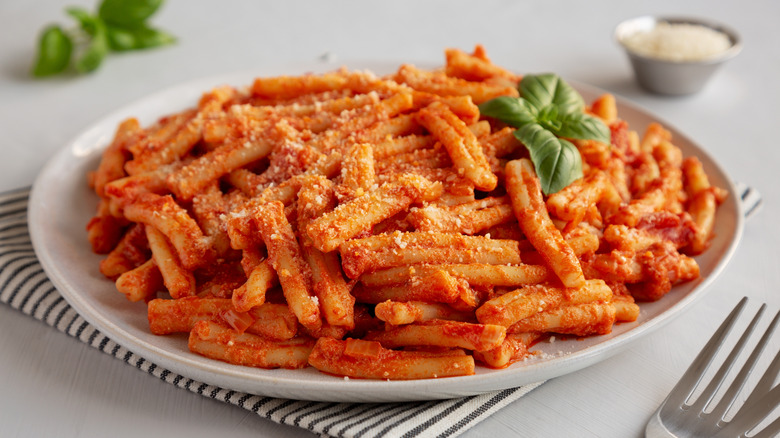 A white plate of pasta in a creamy tomato sauce