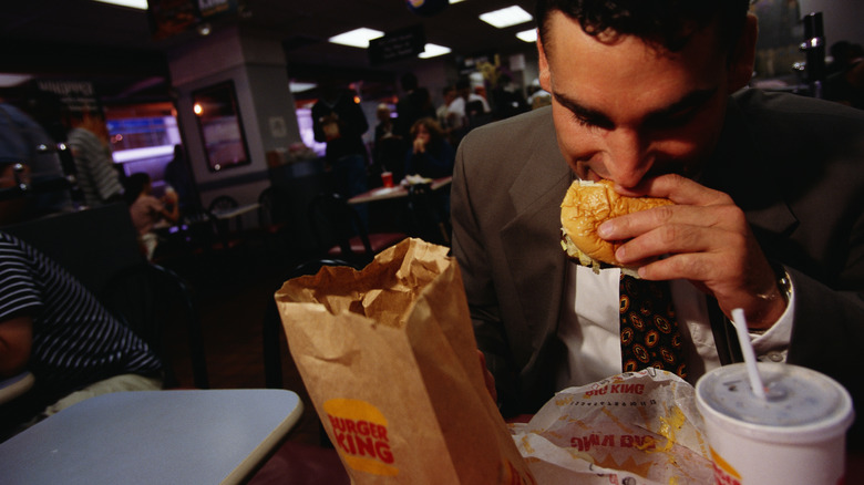 A businessman eats a quick lunch at the busy fast food restaurant.