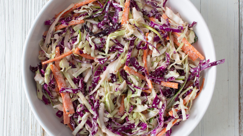A bowl of coleslaw sits on a table.