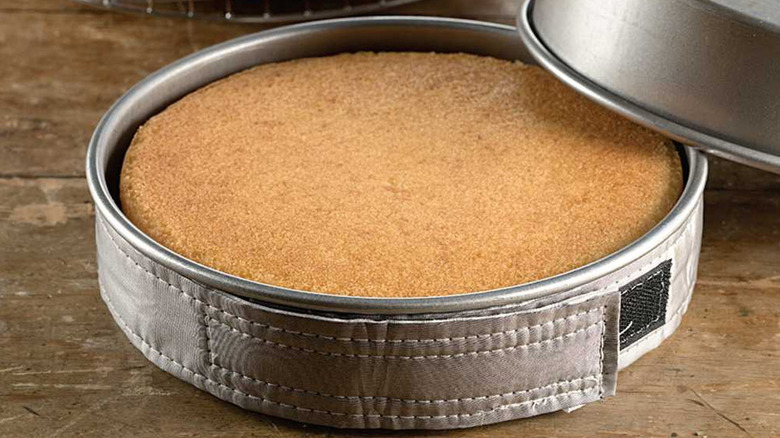 Cake pan with vanilla cake wrapped in cake strips.