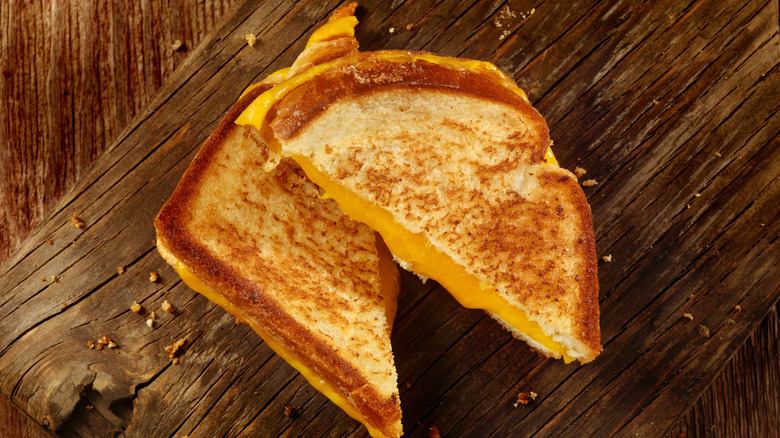 A grilled cheese, sliced into triangles, on a wooden board