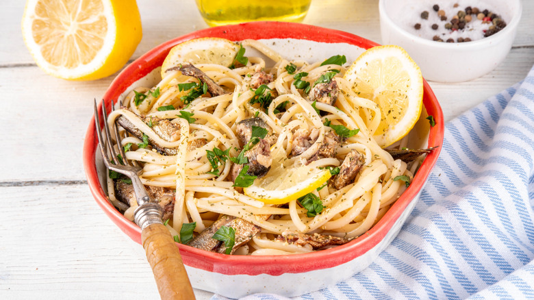 Bowl of spaghetti with lemon, parsley, olive oil and chunks of sardines througout