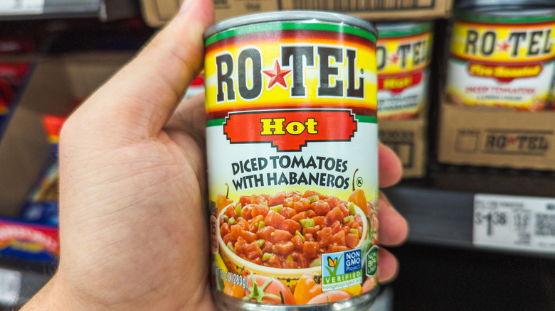 A can of hot Ro-Tel diced tomatoes with habaneros in a hand in a grocery store
