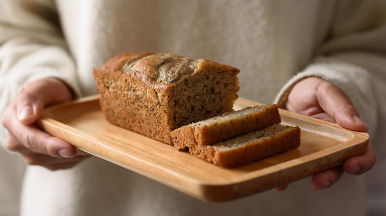 hands holding a plate of sliced banana bread