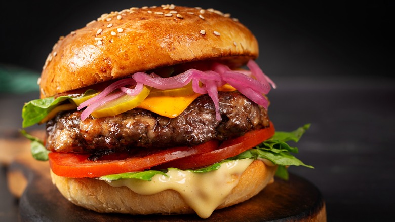 Cheese burger with lettuce, pickled red onion, tomato, pickles, cheese, and sauce