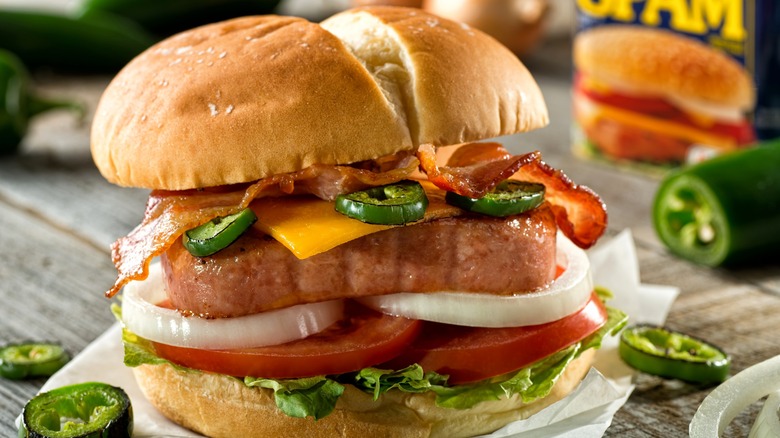 Burger with seared Spam, jalapeños, tomatoes, lettuce, onions, cheese, and bacon