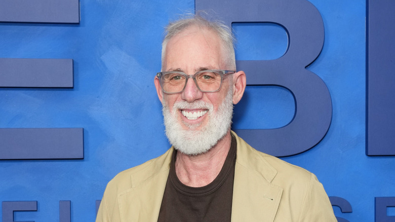 Actor Brian Koppelman smiles in front of a blue wall.