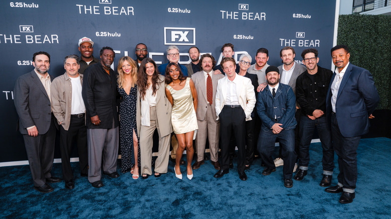 The full cast of The Bear poses together on a blue carpet.