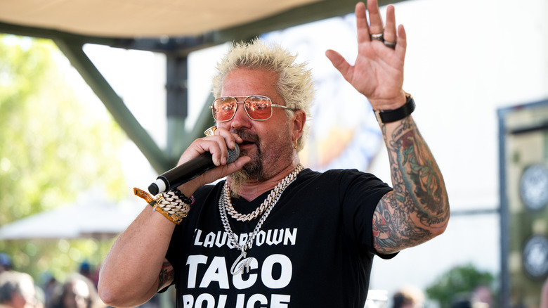 Guy Fieri speaks into a mic at an event