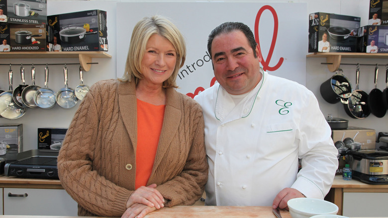 Martha Stewart and Emeril Lagasse smiling on a kitchen set